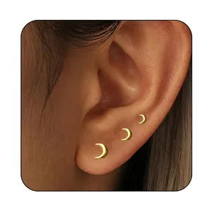 Detailed view of three graduated gold crescent moon studs on a model ear