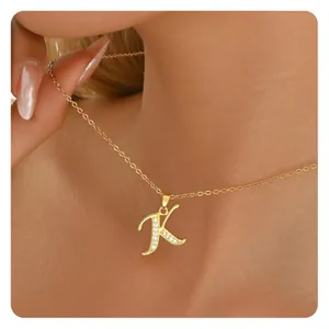 Close-up of gold cursive letter K pendant necklace with sparkling micro-pave zircons