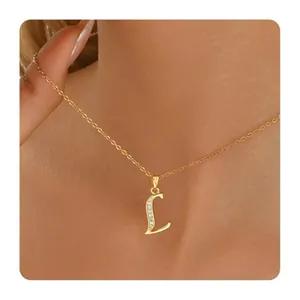 Detail of gold plated letter L pendant necklace with zircon stones on female model