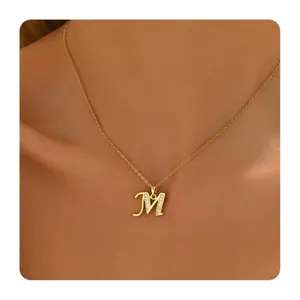 Detail of gold brass necklace with zircon-studded cursive letter M pendant on model
