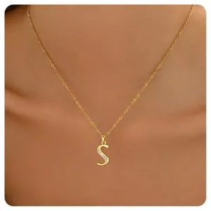 Close-up of a gold-plated necklace featuring a zircon-inlaid letter S pendant on a model
