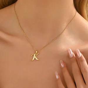 Gold-plated brass necklace with crystal-studded cursive letter K pendant on a model