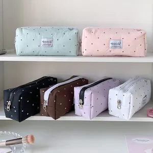 Detailoverzicht van de gestipte etuis en make-uptasjes in zes zachte pastelkleuren