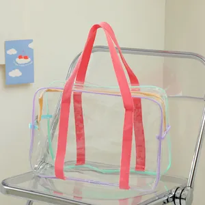 Close-up of a clear PVC tote bag with pink fabric handles and a gold zipper closure