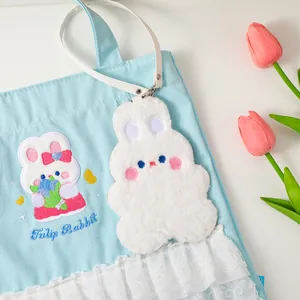 Detail of cute white plush rabbit card holder attached to a lace canvas tote bag