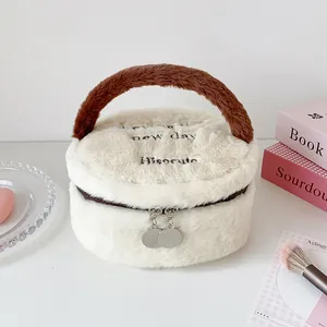 Detalle del neceser de felpa blanco con asa marrón y cremalleras metálicas dobles