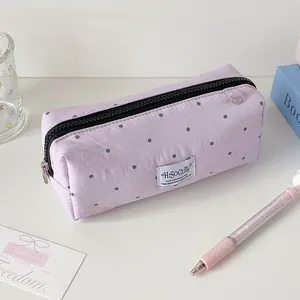 Detail van een lavendelkleurige polkadot etui met metalen rits en minimalistisch label