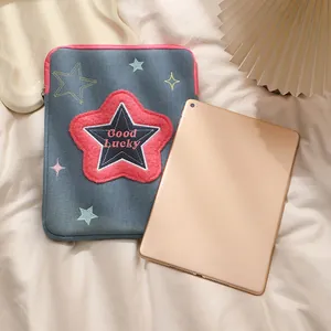Dettaglio custodia iPad in denim grigio con ricamo stella rosa e testo Good Lucky