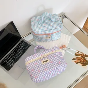 Détail de trousses de toilette matelassées à carreaux avec nœuds roses et double zip