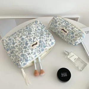 Gros plan sur la texture du tissu matelassé fleuri et les coutures de la trousse de maquillage