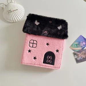 Detail van pluche fotoalbum in de vorm van een huis met vlinderborduurwerk in roze en zwart