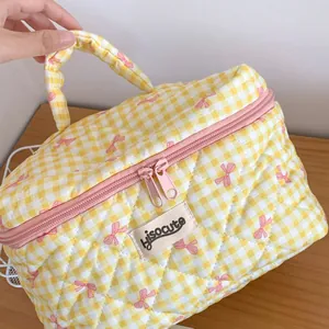 Détail d'une trousse de maquillage matelassée à carreaux jaunes avec des nœuds roses
