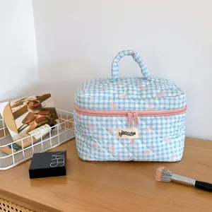 Gros plan sur la trousse de maquillage matelassée à carreaux bleus et nœuds roses