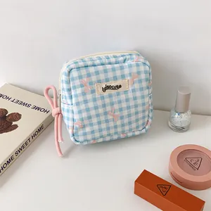 Détail d'une pochette à cosmétiques carrée à carreaux bleus avec motifs de rubans roses