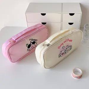 Close-up of pink and beige cartoon dog pencil cases with handles and sweet patterns