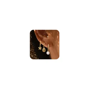 Three-piece gold hoop earring set with starfish, shell, and pearl charms on ear