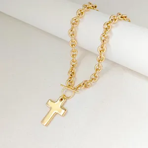 Macro detail of gold-plated cable chain necklace with OT toggle clasp and cross pendant