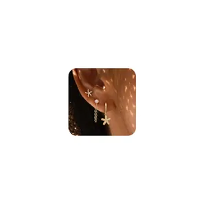Three-piece gold seashell and pearl earring set styled on model with a starfish design