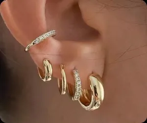 Detailed close-up of layered gold hoop earrings and ear cuffs with micro-pave white zircons