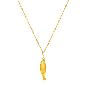 Detailed close-up of a 14k gold plated brass fish pendant with realistic scales and eyes
