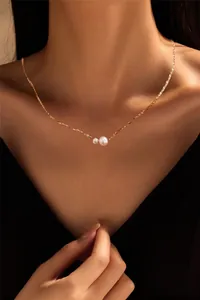 Close-up of elegant gold chain necklace with double white pearls on model's neck