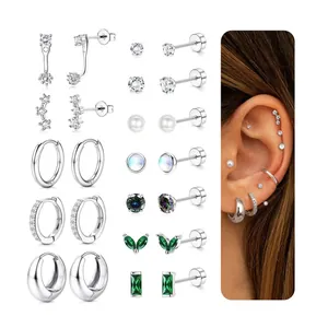 Macro shot of silver stud earrings set featuring pearls, zircons and green gemstones