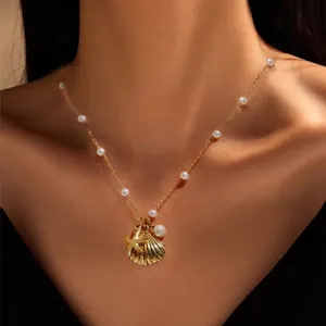 Golden ocean necklace with shell and starfish pendants and white pearls on a model