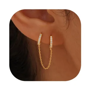 Detail of gold-plated chain earrings with sparkling cubic zirconia on a female ear