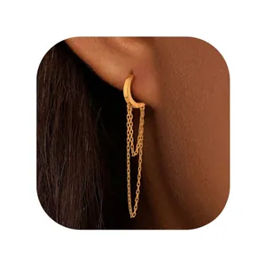 Close-up of golden tassel hoop earrings with long dual chains worn by a model