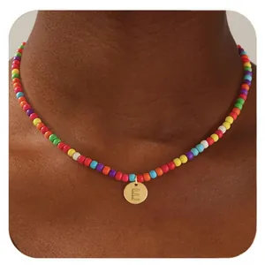 Détail d'un collier de perles multicolores avec pendentif rond doré et lettre E
