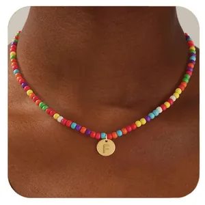 Gros plan du collier de perles colorées avec un pendentif cœur doré et la lettre F