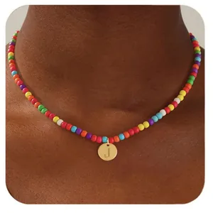 Gros plan d'un collier de perles multicolores avec pendentif doré gravé de la lettre J