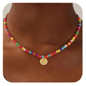 Détail du collier de perles multicolores avec un pendentif rond doré arborant la lettre K