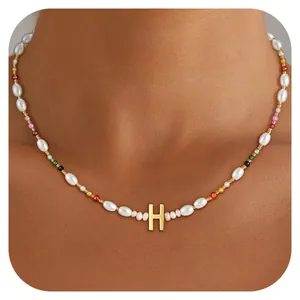 Detail of bohemian beaded necklace featuring baroque pearls and gold letter H pendant