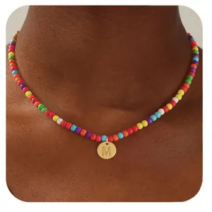 Gros plan d'un collier de perles arc-en-ciel avec pendentif lettre M doré
