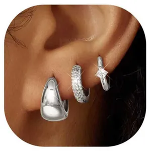Detailed view of three silver teardrop earrings worn together on the earlobe