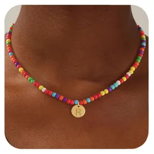 Détail d'un collier de perles colorées avec pendentif lettre R dorée sur modèle