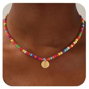 Vue macro d'un collier de perles colorées avec un pendentif doré rond lettre S