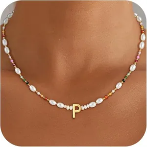 Detail of beaded necklace with irregular pearls and golden letter P on a female model