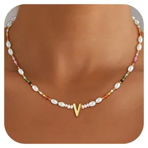 Detail of colorful beads and irregular pearl necklace with gold letter V pendant
