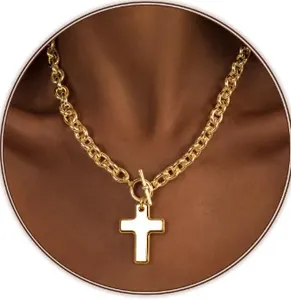 Detail of gold chunky link chain necklace featuring a white cross pendant and toggle clasp