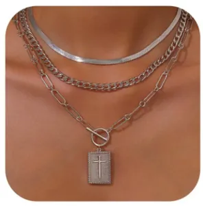 Close-up of triple-layered silver necklace with cross pendant and toggle clasp on neck