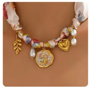 Detail of bohemian silk ribbon necklace with gold charms, leaf, and pearls on a model