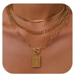 Detail of layered gold-plated necklaces with cross pendant and toggle clasp on model