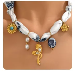 Detail of silk ribbon necklace with gold sunflower, butterfly and ceramic floral charms