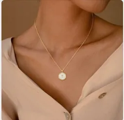 Close-up van een vintage gouden ketting met letter F-hanger en zeshoekige inleg