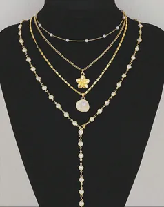 Detailed layered gold necklace set with pearl accents and floral shell charms on a bust