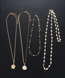 Detail of four-piece layered gold necklace set with floral and shell pearl charms