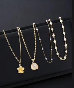 Detail of gold-plated brass necklaces with pearl and shell pendants on black stand