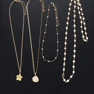 Gold plated brass necklace set featuring shell pendants, pearls, and flower charms